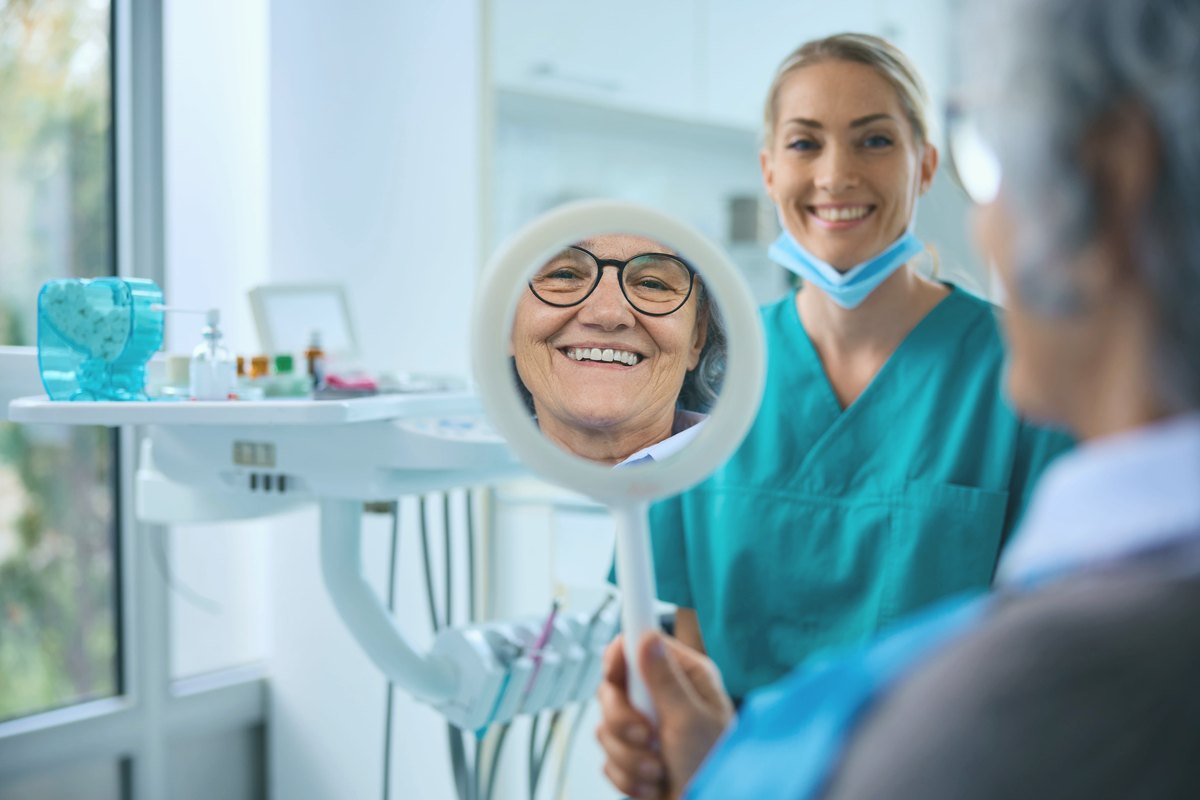 Patient looking at her new smile in a hand mirror