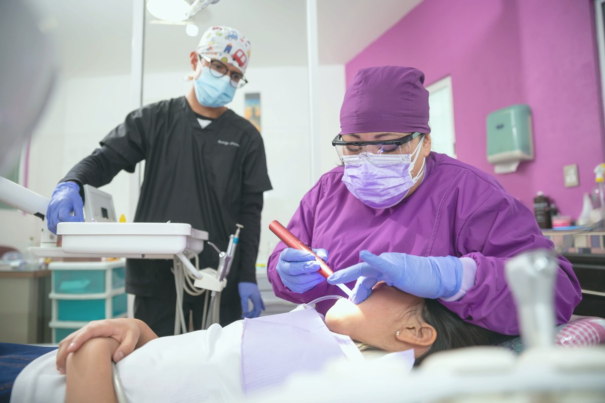 Dentist treating a child patient with an assistant