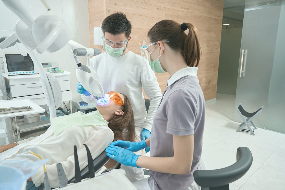 Two clinicians treating a patient in the chair