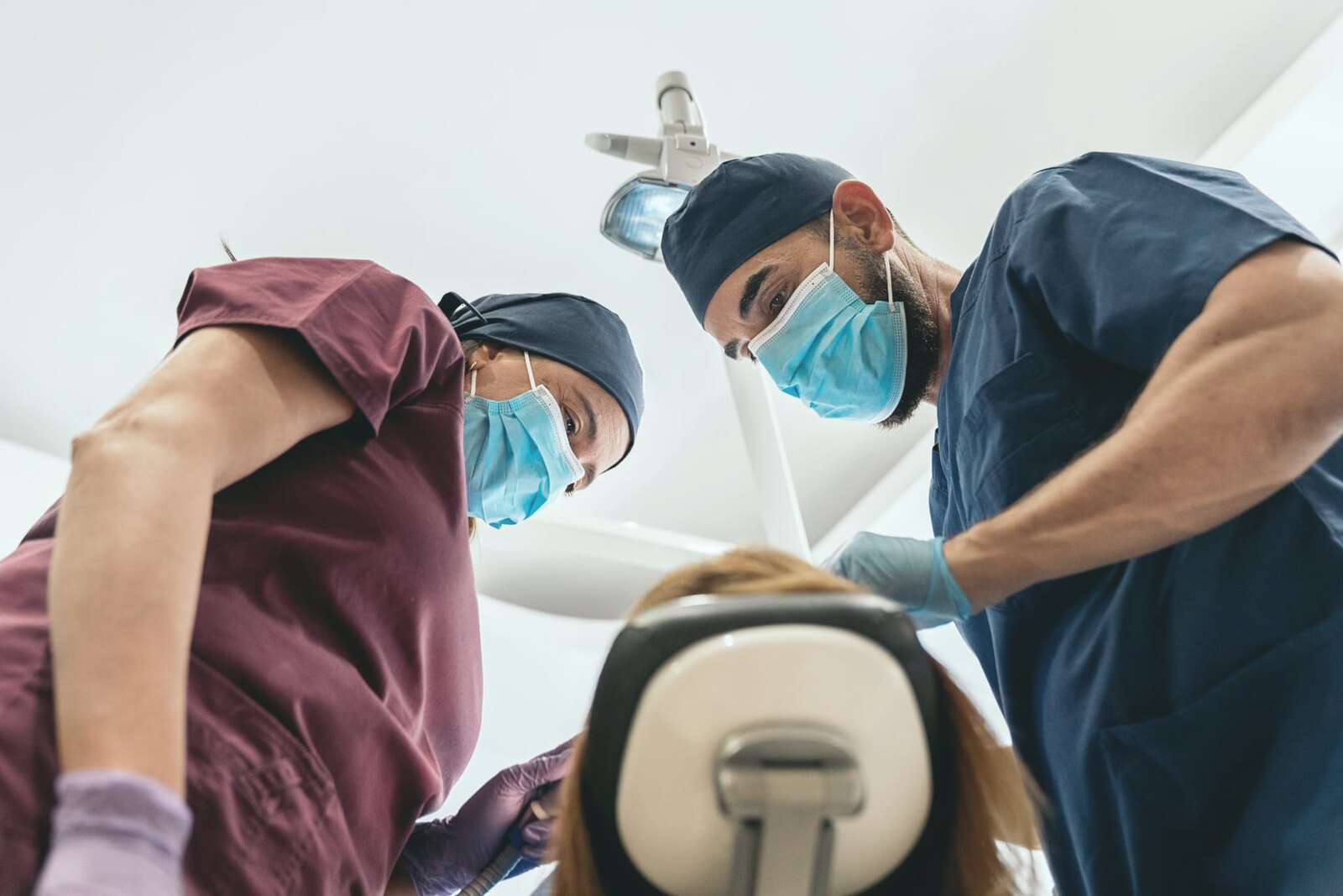 Two clinicians working together over a patient in the chair